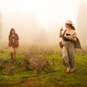 Two girls walking in a misty forest, trees in the background