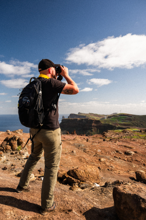 An explorer with binoculars on a rocky island, portrait format