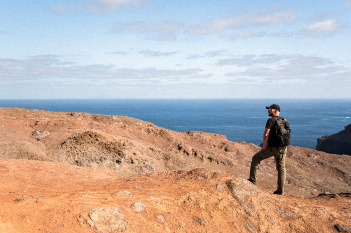 Christoph standing on rocky cliffs by the sea on a sunny day