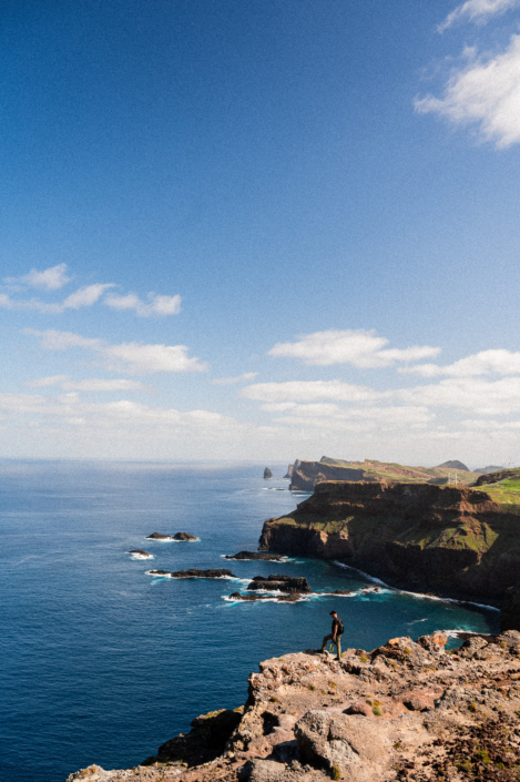The coastal landscape of Madeira island and a man standing on a cliff, portrait format