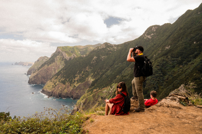A group by the see, mountains in the background, watching out with binoculars