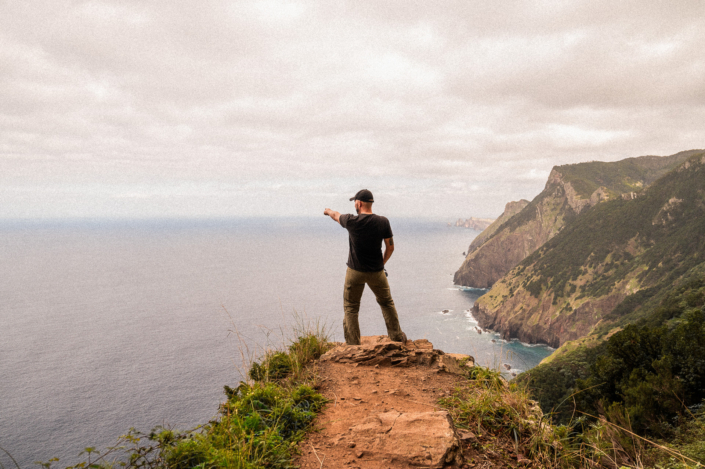 Christoph standing on a cliff, pointing out at sea to where Porto Santo island is