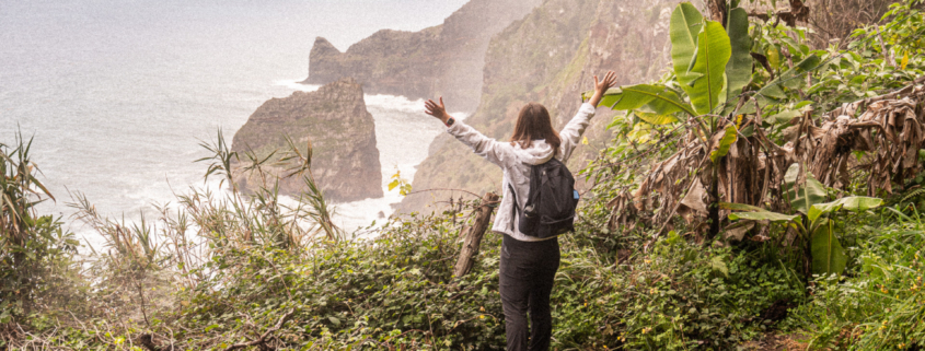 Female Digital Nomad spreading her arms at a stunning ocean view on Madeira island
