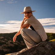 A girl with a white hat sitting on a stone